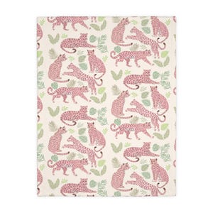 May include: A cream-colored blanket featuring a repeating pattern of pink leopards and green tropical leaves. The leopards are depicted in various poses, creating a playful and stylish design. This blanket is perfect for adding a touch of whimsy to any room.