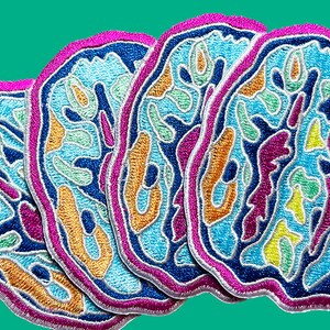 May include: Four embroidered patches in the shape of a brain, each with a different color scheme. The patches are blue, green, yellow, and orange with a white outline. The patches are layered on top of each other.