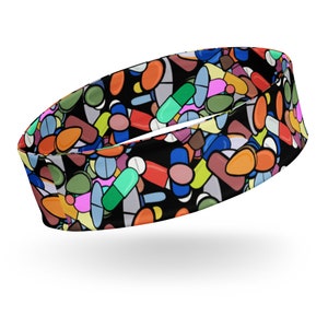 Puede incluir: Una diadema negra con un patrón colorido de píldoras y cápsulas. La diadema está hecha de un material suave y elástico, perfecto para hacer ejercicio o hacer recados.