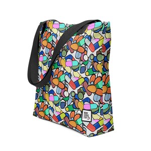 May include: A white tote bag with a colourful pattern of pills and capsules. The bag has black straps and a small logo that says "Nerdy Science Stuff".