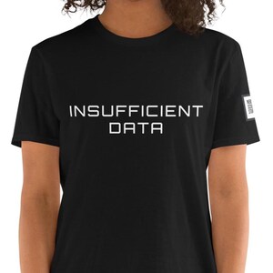Pode incluir: Uma t-shirt preta de manga curta com o texto branco INSUFFICIENT DATA impresso numa fonte sem serifa clara no peito. Uma pequena etiqueta quadrada branca com texto preto é visível na manga esquerda da peça de vestuário.