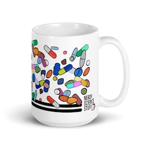May include: White ceramic mug featuring a colourful design of pills and capsules. The mug has black stripes and the text "Nerdy Science Stuff" on the bottom right side.