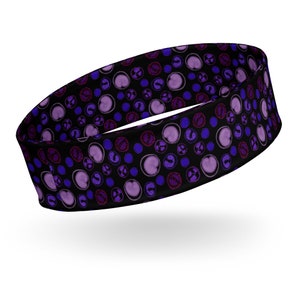 Puede incluir: Una diadema negra con un patrón repetido de círculos y corazones morados y rosas.