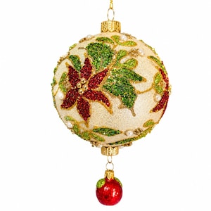 May include: A spherical Christmas ornament with a cream-colored glittery base, decorated with red glitter poinsettia flowers and green glitter leaves. Small white faux pearls are scattered across the surface. A small red ball hangs from the bottom.