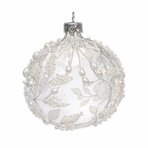 May include: Clear glass Christmas ornament with a silver cap. The ornament is decorated with white faux pearls and beaded floral designs. The ornament is round and has a reflective surface.