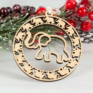 May include: A wooden Christmas ornament shaped like a circle with a large elephant cutout in the center. The elephant is surrounded by a ring of smaller elephants.