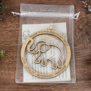 Op de afbeelding: Houten ornament in de vorm van een olifant met de tekst "Thank you for being in my circle" en "Love, Loyalty, Sisterhood, Friendship" rondom de olifant. Het ornament zit in een witte organza zak.