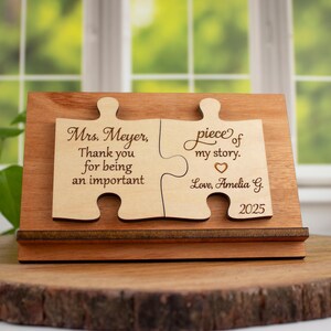 May include: A wooden puzzle piece with the text "Mrs. Meyer, Thank you for being an important piece of my story. Love, Amelia G. 2025" engraved on it.