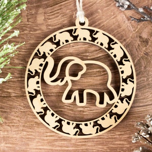 May include: A wooden Christmas ornament shaped like a circle with a large elephant cutout in the center. The elephant is surrounded by a ring of smaller elephant cutouts.