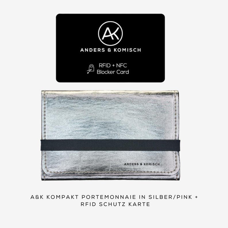 May include: A silver wallet with a black elastic band and a black card with the text "ANDERS & KOMISCH" and "RFID + NFC Blocker Card". The wallet has the text "ANDERS & KOMISCH" on it. The wallet is a compact size.