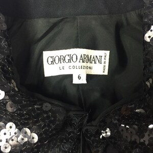 May include: Black sequined top with a label that reads "Giorgio Armani Le Collezioni Made in Italy" and a size tag that says "6".