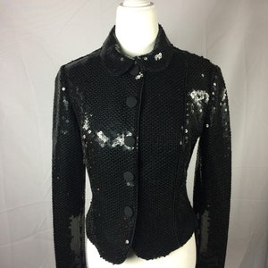 May include: A black sequined jacket with a button closure and long sleeves.