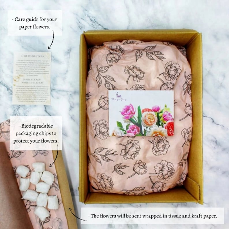 May include: A brown cardboard box with a pink tissue paper lining. The tissue paper has a floral pattern. The box contains white biodegradable packing chips and a card with the text "Flowers for Design".