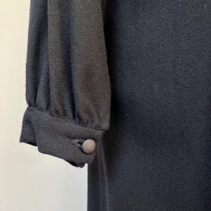 May include: Black long-sleeved dress with a button on the sleeve.