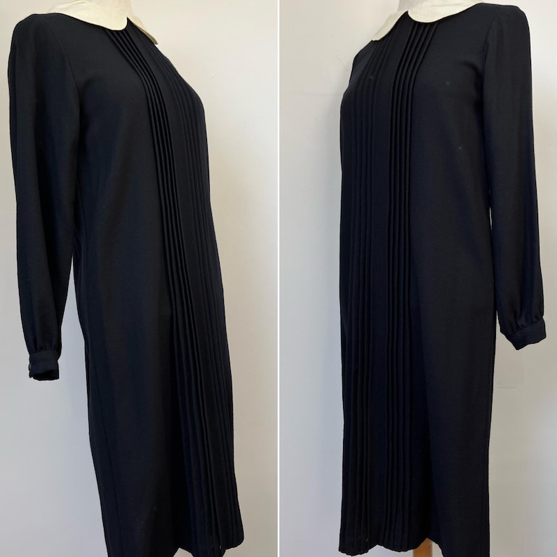 May include: A black pleated dress with a white Peter Pan collar and long sleeves.
