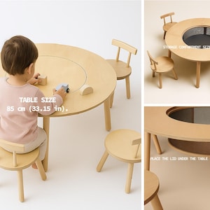 Puede incluir: Una mesa redonda de madera clara con un diámetro de 85 cm y cuatro sillas a juego. La mesa cuenta con una tapa circular central que revela un compartimento de almacenamiento. El texto dice TABLE SIZE 85 cm (33.15 in.) y PLACE THE LID UNDER THE TABLE - QUICK AND EASY.