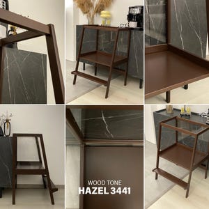 May include: A dark brown wooden step stool featuring a two-tier design with a wide top platform and a lower step. The frame is constructed with angled side supports. The text WOOD TONE HAZEL 3441 is printed on the surface of the stool structure.
