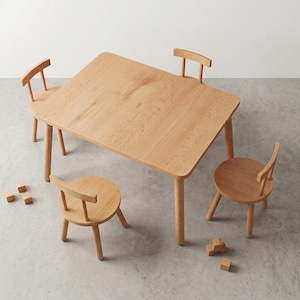 Puede incluir: Una mesa de madera de tono claro con esquinas redondeadas y cuatro sillas a juego con respaldos curvos. El conjunto de muebles está dispuesto con tres sillas alrededor de la mesa rectangular, junto a varios bloques de madera pequeños esparcidos.