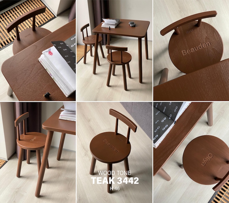 May include: A dark brown wooden table and two matching chairs with circular seats and curved backrests. The seats are engraved with the names Beauden and Oiya. The text WOOD TONE TEAK 3442 H 46 is visible on one of the chair seats.