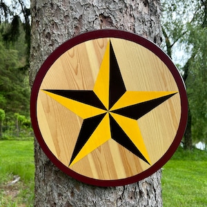 May include: A round wooden sign with a red border and a large yellow and black five-pointed star in the center.
