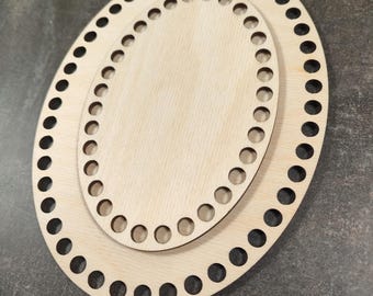 Könnte beinhalten: Zwei ovale Korbunterseiten aus hellem Holz. Die größere Basis hat eine Reihe von gleichmäßig verteilten Löchern am Umfang. Die kleinere Basis, ebenfalls oval, liegt obenauf.