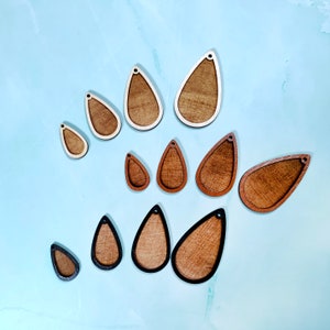 Op de afbeelding: Assortiment van houten oorknop-blanks in druppelvorm in verschillende maten. De blanks zijn onbewerkt en klaar om te worden geschilderd, gebeitst of versierd.
