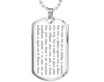 May include: A silver necklace with a dog tag pendant featuring a religious inscription in black text. The inscription reads "Our Father, who art in heaven, hallowed be thy name, thy kingdom come, thy will be done on earth as it is in heaven. Give us this day our daily bread, and forgive us our trespasses, as we forgive those who trespass against us. And lead us not into temptation, but deliver us from evil. Amen."