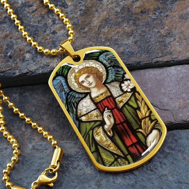 Puede incluir: Collar de cadena dorada con un colgante de placa de identificaci&oacute;n dorada que presenta una imagen de vitral de un &aacute;ngel con alas, un halo y una t&uacute;nica verde y roja.