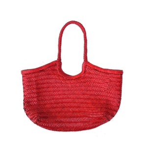 Puede incluir: Un bolso tote tejido de color rojo vibrante con una base redondeada y dos asas trenzadas. El bolso está hecho de un material tejido apretado, creando una superficie texturizada. Las asas están unidas a la parte superior del bolso.