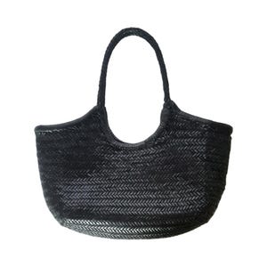 May include: Black woven tote bag with a braided handle. The bag has a rounded shape and a textured, basket-weave design. The handle is attached to the bag with a curved, reinforced section. The bag is made of a dark material.