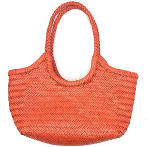 May include: A woven orange tote bag with braided handles. The bag features a basket weave pattern and a rounded shape. The handles are thick and sturdy, designed for comfortable carrying. The bag is made of a durable material.