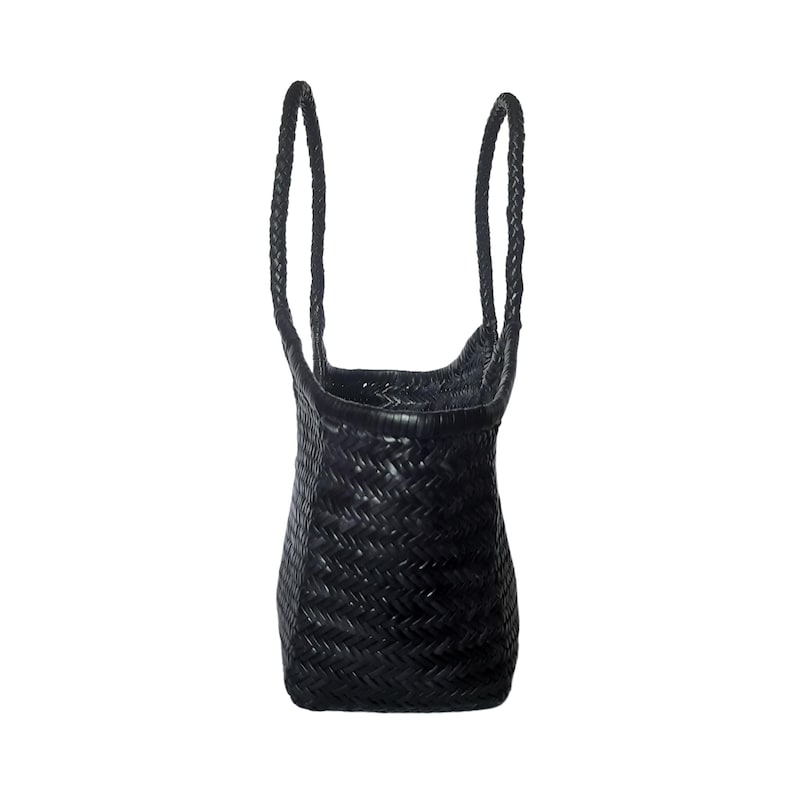 May include: Black woven tote bag with braided handles. The bag has a rectangular base and a slightly flared top. The weave pattern is tight and consistent, giving the bag a structured appearance. The handles are long enough to be worn over the shoulder.