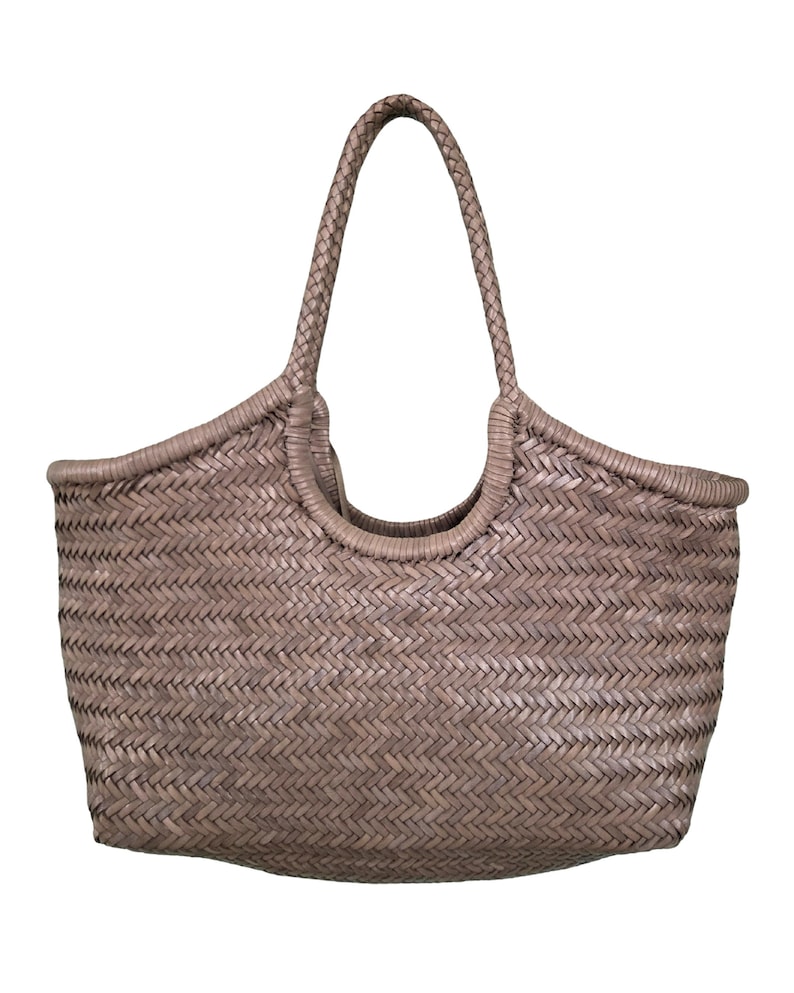 May include: A woven tote bag in a neutral taupe color. The bag features a braided handle and a basket weave design. The open top bag is suitable for carrying groceries or other items. The bag is made of a durable material.