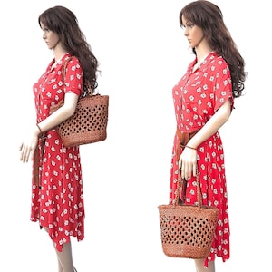 May include: A red floral print dress with a brown belt and a woven brown tote bag. The dress has short sleeves and a collared neckline. The tote bag has a woven design and two handles.