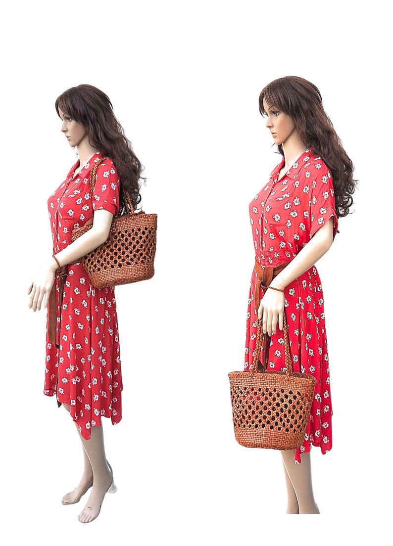 May include: A red floral print dress with a brown belt and a woven brown tote bag. The dress has short sleeves and a collared neckline. The tote bag has a woven design and two handles.