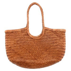 May include: A woven brown tote bag with a braided handle. The bag has a rounded shape and a textured surface created by the woven pattern. The handle is arched and attached to the top of the bag.