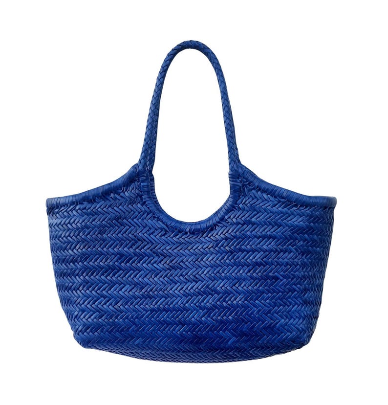 May include: A vibrant blue woven tote bag with a braided handle. The bag features a textured, basket-weave design and a curved top edge. The bag is a solid, bright blue color, perfect for carrying items.