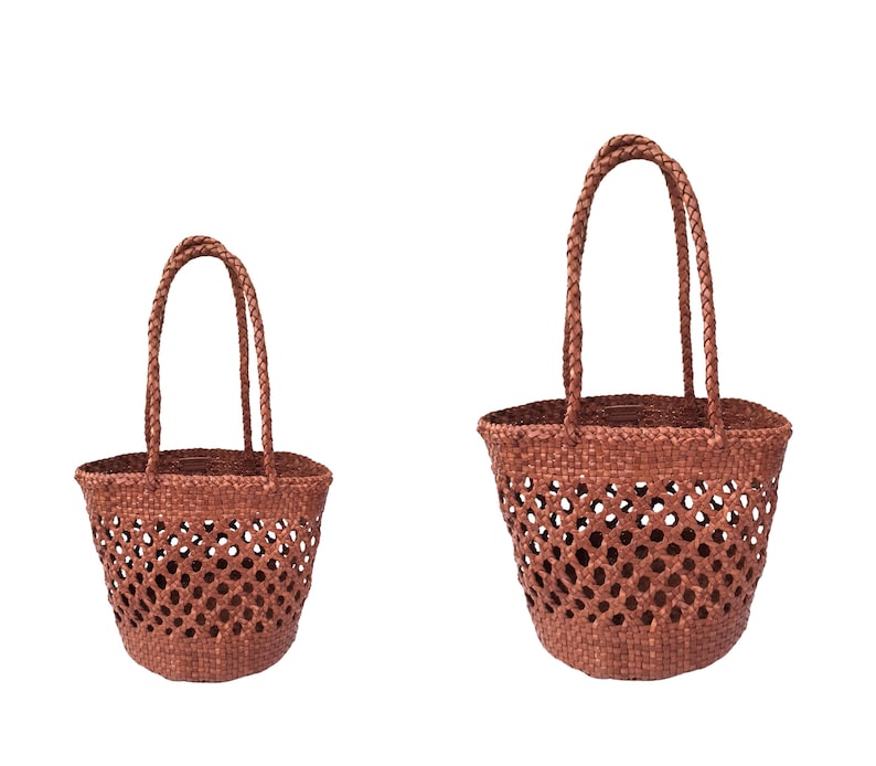 May include: Two woven brown tote bags with braided handles. The bags have an open weave design, allowing visibility of the contents. The bags are made of a natural material, likely straw or a similar fiber.