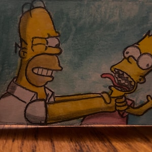 May include: Hand-painted artwork depicting Homer Simpson choking Bart Simpson. Homer is yellow with a white shirt and Bart is yellow with a red shirt. The background is a light teal colour. The artwork is on a wooden surface.