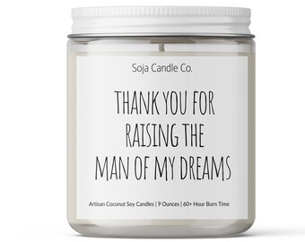 May include: A clear glass jar candle with a white lid. The label reads "THANK YOU FOR RAISING THE MAN OF MY DREAMS." The candle is 9 ounces and has a 60-hour burn time. The candle is made with artisan coconut soy.