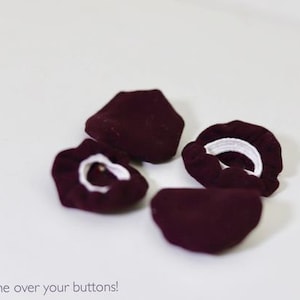 May include: Four burgundy fabric button covers with white elastic bands.  "Slip me over your buttons!" is written below the image.