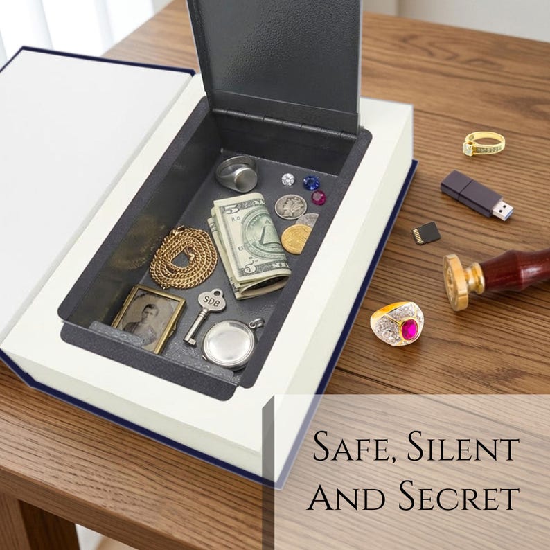 May include: A hollow book safe with a dark interior containing a folded five-dollar bill, a gold chain, a silver key marked SDB, a small framed portrait, a silver locket, and loose coins. Outside are two gold rings, a USB drive, and a wax seal stamp.