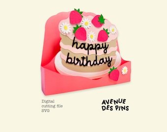 May include: A paper cake with pink frosting, strawberries, and daisies, with the words "happy birthday" in black script. The cake sits in a pink card holder. The image also includes the text "Digital cutting file SVG" and the logo "AVENUE DES PINS".