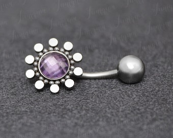 May include: A silver belly button ring with a purple gemstone in the center of a circular design.