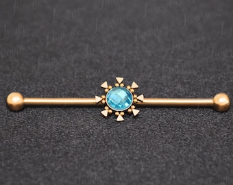 Puede incluir: Barbell de oro con una gema azul y un diseño de estrella.