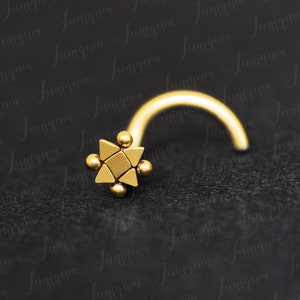 Puede incluir: Anillo de nariz de oro con un diseño de estrella geométrica. La estrella está hecha de varios triángulos pequeños y tiene una superficie texturizada.