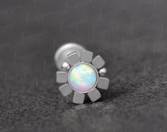 Pode incluir: Uma peça de joalheria corporal de prata com um design em forma de flor e uma pedra de opala branca no centro.