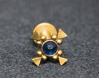 May include: Gold body jewelry with a blue gemstone in the center and four gold triangles around it.