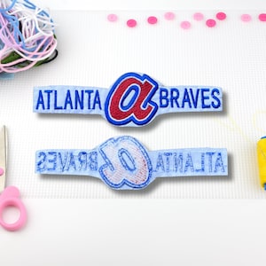 May include: Two blue and white embroidered patches with the text "Atlanta Braves" and a red and white embroidered patch with the text "Atlanta Braves" and a stylized "A".