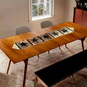 May include: A brown leather table runner with black star cutouts. The runner is on a wooden table with two chairs and a bench.